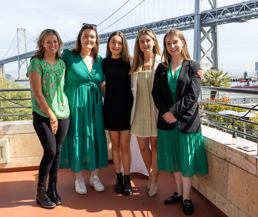 5 women wearing green with the Bay Bridge in the background